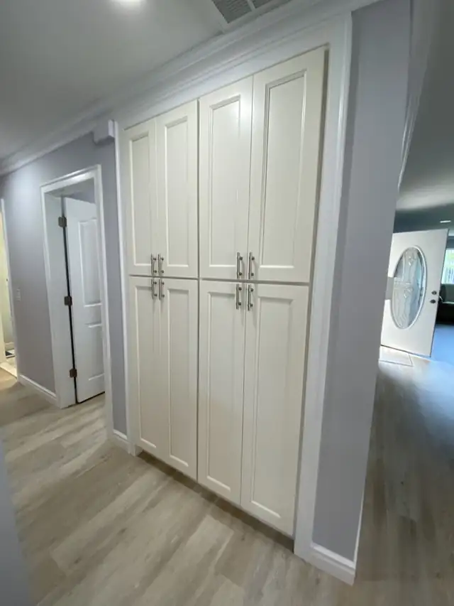 Tall white shaker pantry cabinets with brushed nickel pulls in a hallway